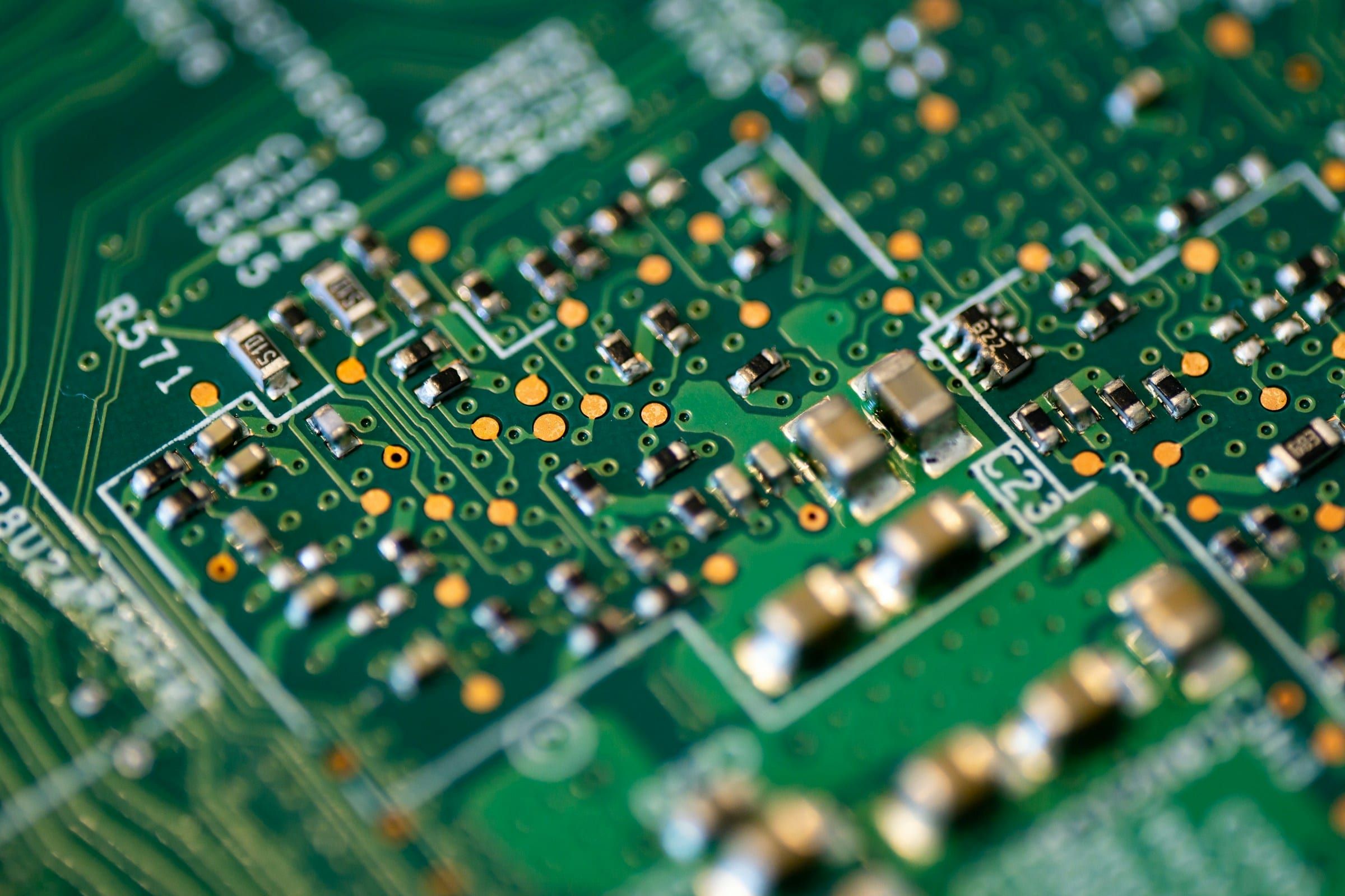 Macro of a green printed circuit board with surface-mount resistors, capacitors and solder pads